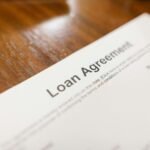 Detailed loan agreement document close-up on a wooden table representing legal and financial concepts.